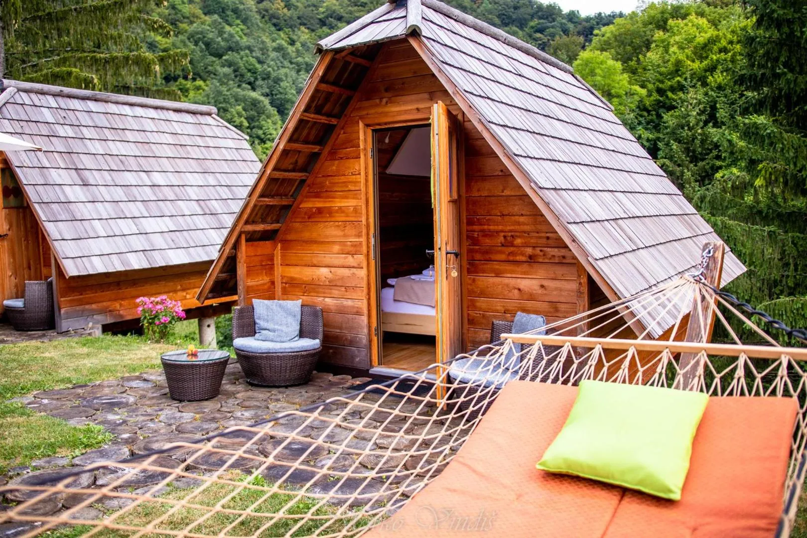 Macesnova glamping hiška s svojo majhno teraso med drevesi v haloških gričih.